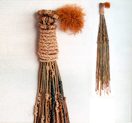 <em>Quipu</em> enrollado con pluma roja, tal como se los guardaba cuando se completaba su uso. Colección Museo Nacional de Arqueología, Antropología e Historia del Perú. Fotografía, tomada de C. Arellano, 1999.