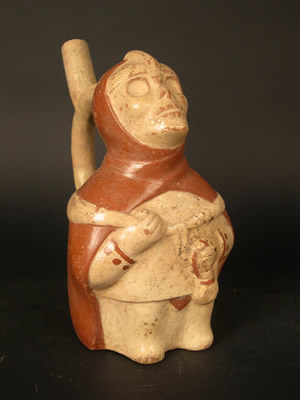 Botella asa-estribo: Hombre esqueletizado con capucha roja, túnica y tapar rabo cargando ofrendas funerarias. Museo Larco, Lima – Perú / ML002285