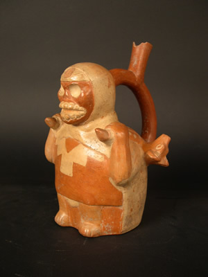 Botella asa-estribo: Hombre esqueletizado con capucha roja, túnica y tapar rabo cargando ofrendas funerarias. Museo Larco, Lima – Perú / ML002285