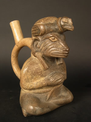 Botella asa-estribo: «Iguana» sentado con tocado de cóndor, orejeras, túnica y bulto en la espalda. Museo Larco, Lima – Perú / ML004122