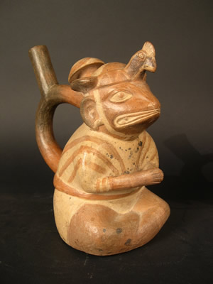 Botella asa-estriba: «Iguana» sentado con tocado de ave y cabezal de porra, túnica y bulto en la espalda. Museo Larco, Lima – Perú I ML004124