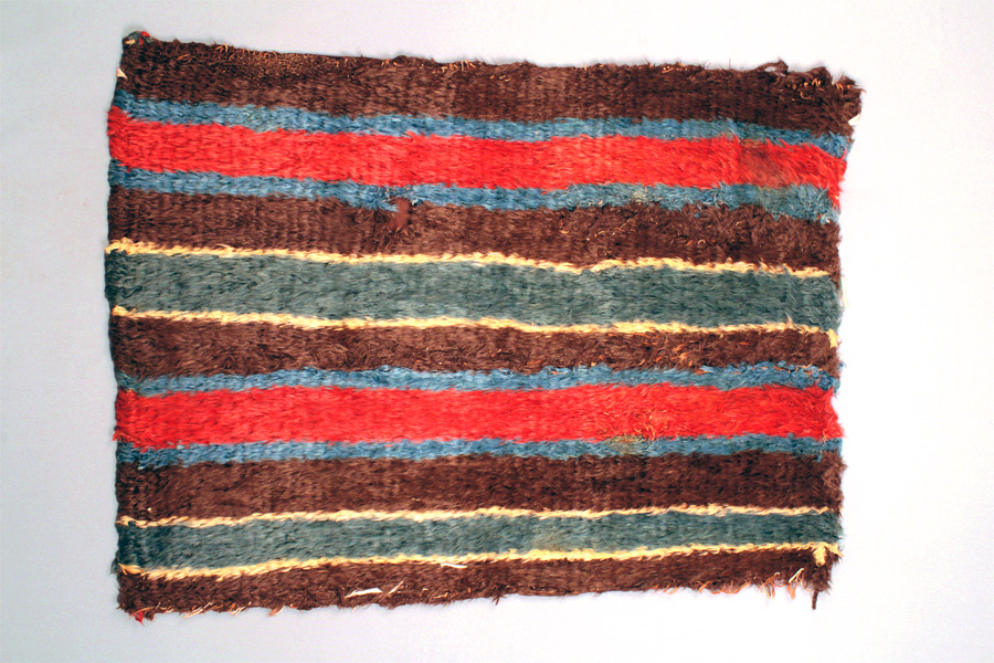 Manta listada policroma. Tejido faz de urdimbre con agregados de mechas, fibra de camélido. Río Loa Medio, 400 a.C.- 500 d.C. 66 x 95 cm, MCHAP 3565.
