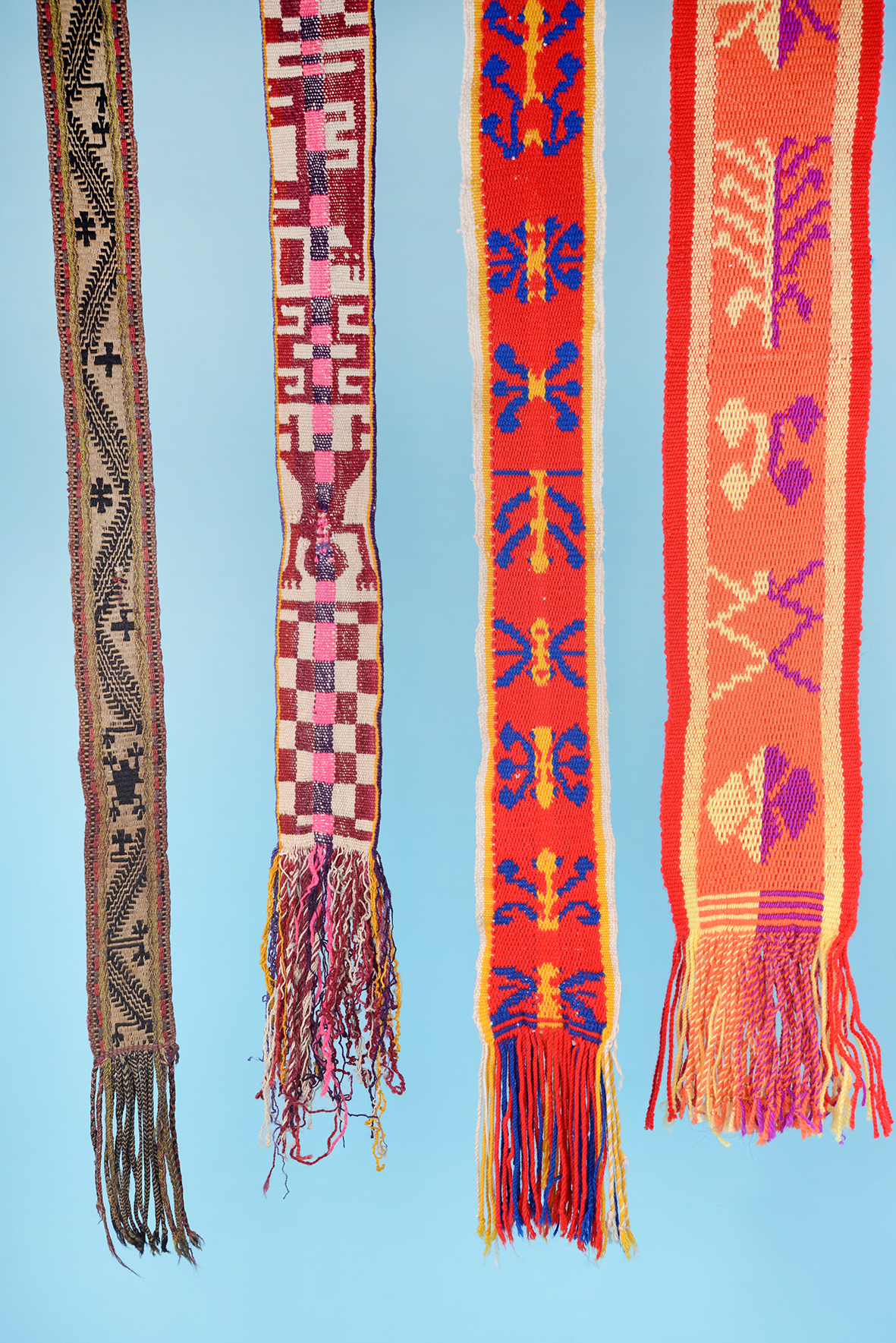 Three sashes of sheep's wool. Trarüwe. Unknown artist | Mapuche, 1900–1950. MCHAP, 1768, 1691, 2142. The fourth sash (far right): Cristina Manquepi | Mapuche, 2025. Photograph by Justine Graham.